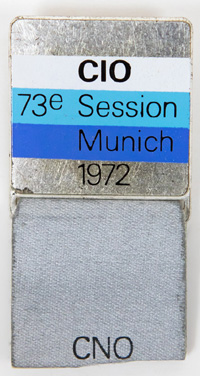 Teilnehmer-Abzeichen der 73e Session I.O.C. Munich 1972. Stoffband mit Aufdruck "CNO" (NOK). Edelstahl, farbig emailliert. 5,5x3 cm.