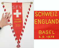 Original Spielwimpel der schweizer Nationalmannschaft vom Fuballspiel Schweiz - England (1:2) am 3.9.1975 in Basel. Zweifarbige Seide mit aufgesetztem, bestickten Verbandslogo. Seidenfransen und gelb gestickter Spielpaarung. Holzstange mit Seidenband. 47x