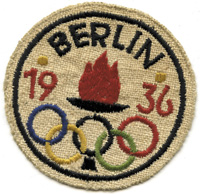 Farbig besticktes Stoffabzeichen "Olympia 1936" mit der Olympischen Flamme und den Ringen. Leinen.7,5 cm.<br>-- Schtzpreis: 70,00  --