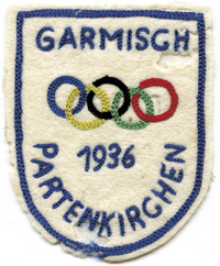 Farbig besticktes Stoffabzeichen "Garmisch-Partenkirchen 1936" mit Olympischen Ringen. 8x6,5 cm.