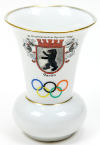 Kleine Vase aus Porzellan mit der Inschrift XI. Olympische Spiele 1936 Berlin mit farbigen Olympischen Ringen und dem Stadtwappen von Berlin. Hersteller: "BL", Hhe: 10,5 cm.