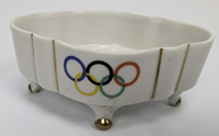 Kleines, vierfiges Porzellanschlchen mit Goldverzierungen und farbigen Olympischen Ringen. Hersteller: "Johann Haviland Bavaria". 10x7x4,2 cm.