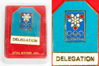Teilnehmerabzeichen Olympische Winterspiele Grenoble 1968 Delegation. Bronze, vergoldet, blau emailliert. 5x3,5 cm. In original Kunststoffbox mit vergoldetem Aufdruck "Arthus Bertrand - Paris". 7x5x1,8 cm.