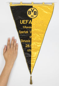 Bestickter Spielwimpel  "UEFA Cup. 1.Runde, 2.Spiel Spartak Vladikavakaz und Borussia Dortmund. 28.9.1993. A.Ponnet" mit aufgesetztem, besticktem Vereinslogo. Zweifarbiger Seidenwimpel mit schwarz-gelber Seidenbordre, Goldbrokatleiste und Goldbrokatbommel