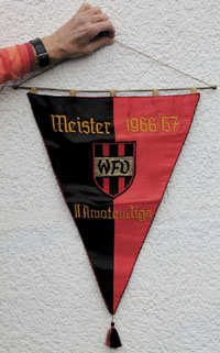 Offizieller Meisterschaftswimpel des Westdeutschen Fuballverbandes 1967 mit aufgestickter Inschrift "Meister 1966/67 II.Amateurliga". Mit aufgesetztem besticktem Verbandswappen "WFV". Seidenwimpel mit schwarz-weier Seidenbommel, Goldbrokatschlaufen. Mess